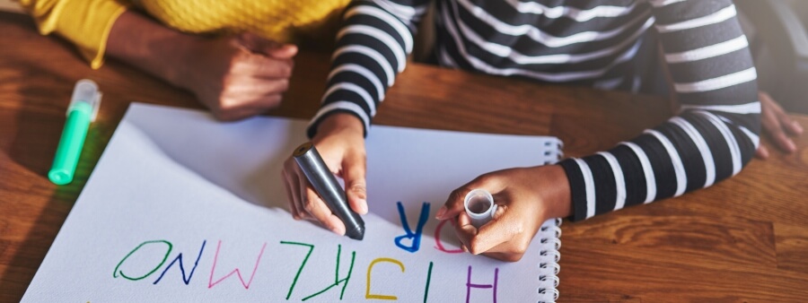 Alfabetização: criança escrevendo letras