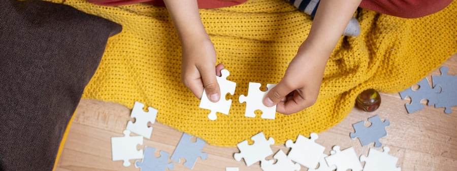 Quebra-cabeça: mãos infantis segurando peças de quebra-cabeça