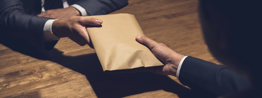 Lei Anticorrupção: imagem de mãos entregando envelope a outra