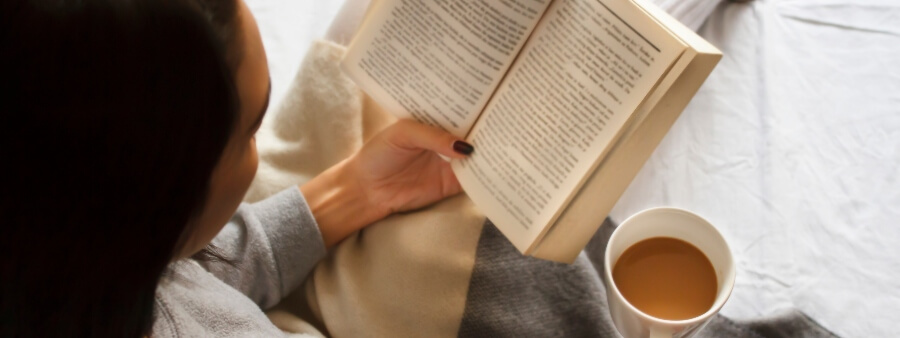 benefícios da leitura para a saúde mental: mulher lendo com xícara de café