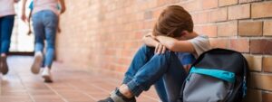 Bullying na escola: criança sentada de cabeça baixa em escola