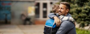 adaptação escolar: pai abraçando filho em escola