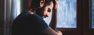 Como lidar com as frustrações: homem triste olhando na janela