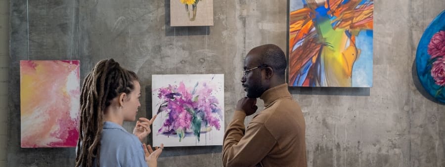 Frases sobre arte: casal em meio a quadros em galeria de arte